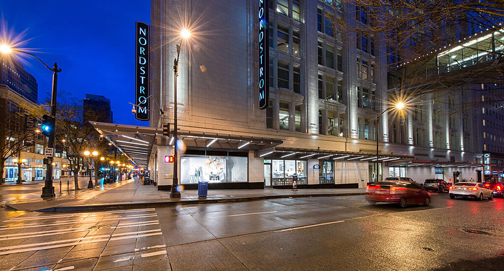 picture of outside Nordstrom building in downtown Seattle with cars driving past