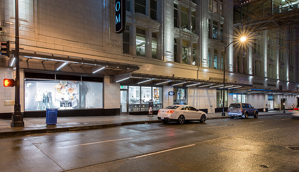 picture of outside Nordstrom building in downtown Seattle with cars driving past