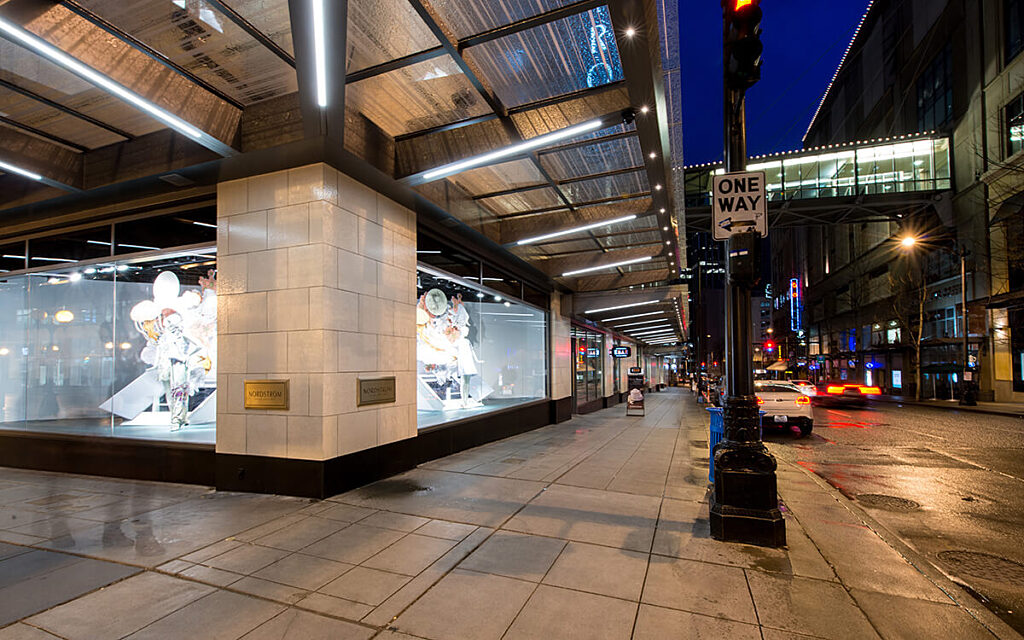picture of outside Nordstrom building in downtown Seattle with cars driving past