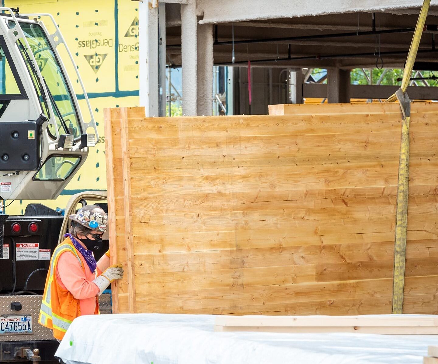 Construction worker unloading and inspecting cross-laminated timber (CLT) panel