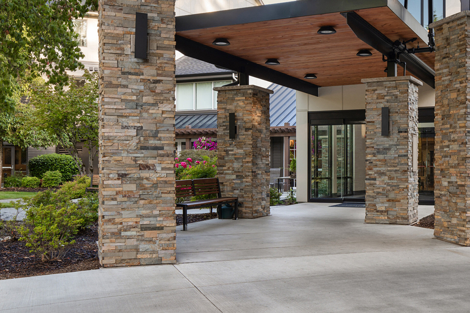 Entrance to a senior living facility with large timber canopies over the driveway