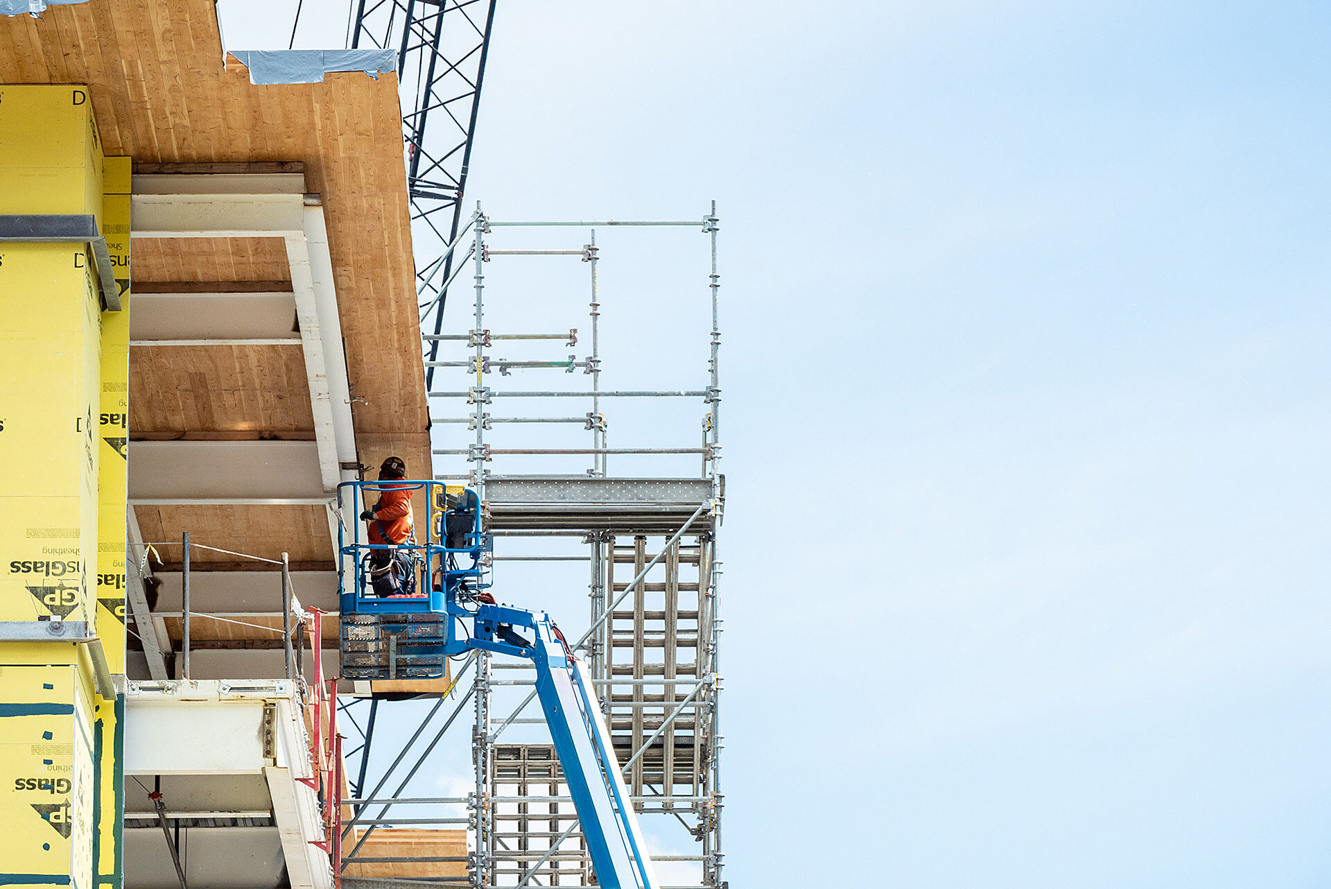 Photo of construction worker in man-lift inspecting roof of work in progress office building