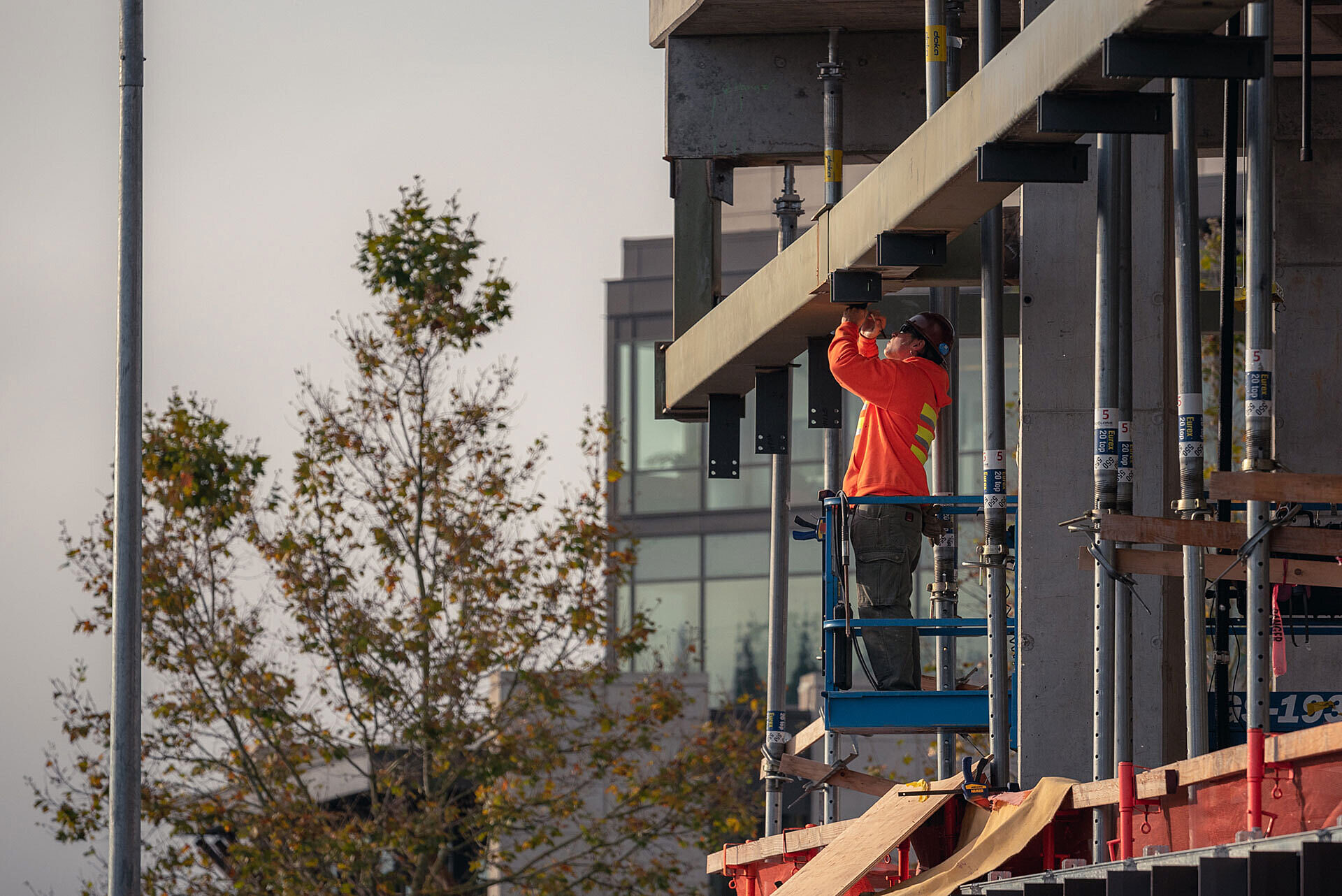 Photo of construction worker in man-lift working on shell of work in progress building
