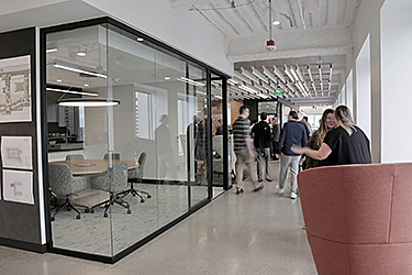 People talking outside a conference room in a professional office.
