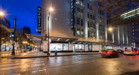 picture of outside Nordstrom building in downtown Seattle with cars driving past