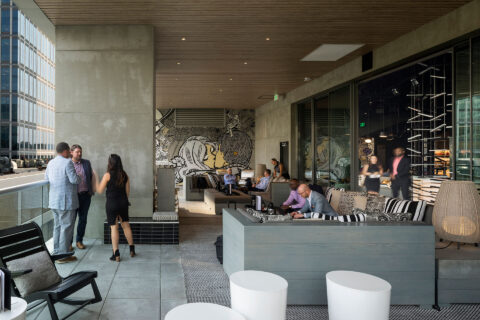 Exterior photo of covered patio area in urban environment with people sitting and conversing
