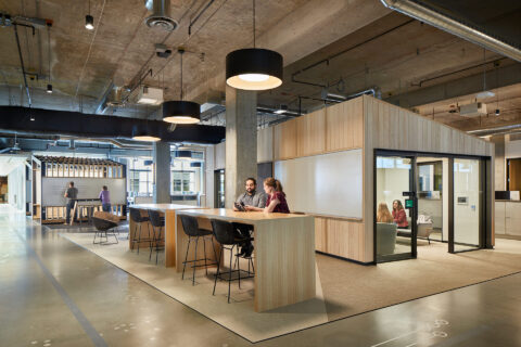 Interior photo of modern office space with two people sitting at table conversing