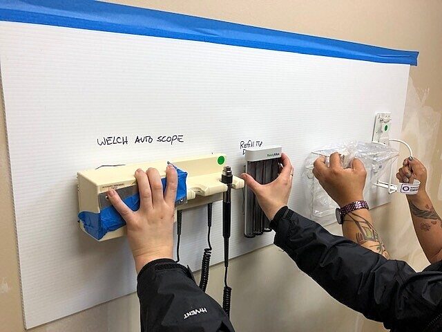 people holding medical tools against wall to decide where to install them in a patient room